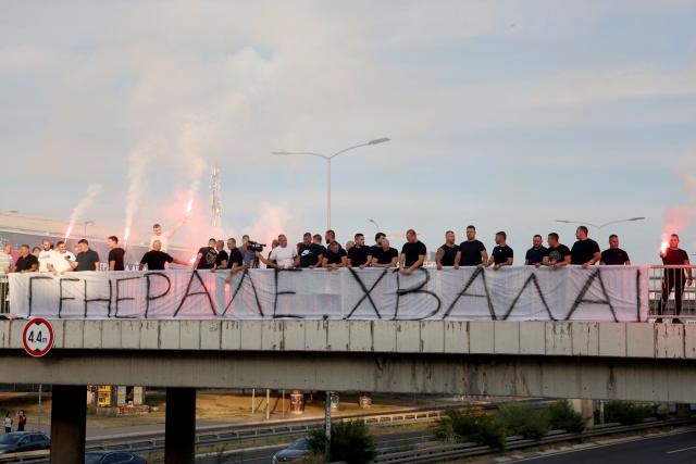 A group of people gathered on a footbridge over a motorway light flares while holding a banner reading "Thank you general" as they greet a convoy carrying the body of Bosnian Serb war criminal Ratko Mladic as it passes through Belgrade, Serbia, on September 3, 2026. Mladic's body arrived in Serbia earlier in the day and was driven from the airport under police escort after being received with military honours. Mladic died the previous week while serving a life sentence for genocide, war crimes and crimes against humanity committed during the 1992-1995 Bosnian war. (Photo by Pedja MILOSAVLJEVIC / AFP)
