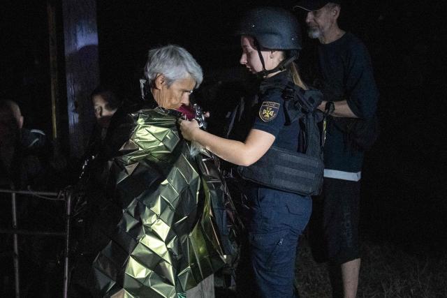 A Ukrainian emergency service worker assists an elderly person outside a damaged residential building following a Russian strike in Kyiv on September 3, 2026, amid the Russian invasion of Ukraine. (Photo by Vladyslav Musiienko / AFP)