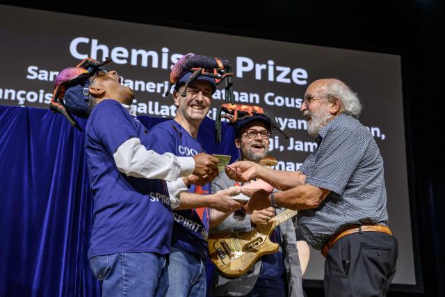 Indian Professor Subramanian Ramaswamy (L) Leonard Chavas (C) and doctor Nathan Coussens (2nd R) receive their prize from 2019 Nobel Prize in Physics Michel Mayor (far R) during the 2026 Ig Nobel Prize Ceremony in Zurich, on September 3, 2026. The team were awarded with the Ig Nobel Chemistry prize award for discovering that milk proteins from vivaparous cockroaches packs three times as much energy as milk proteins from cows. The Ig Nobel Prize is a parody of the Nobel Prize, which is awarded every autumn to celebrate ten unusual or trivial achievements in scientific research. (Photo by Fabrice COFFRINI / AFP)