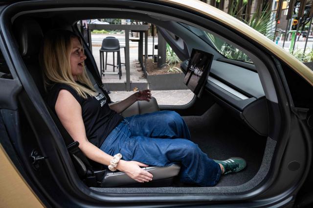 A woman sits inside a Tesla's "Cybercab" as it's displayed in downtown Austin, Texas, on September 3, 2026. Tesla is launching the "Cybercab" which is a taxi with no steering wheel or pedals, designed purely for autonomy. (Photo by RONALDO SCHEMIDT / AFP)