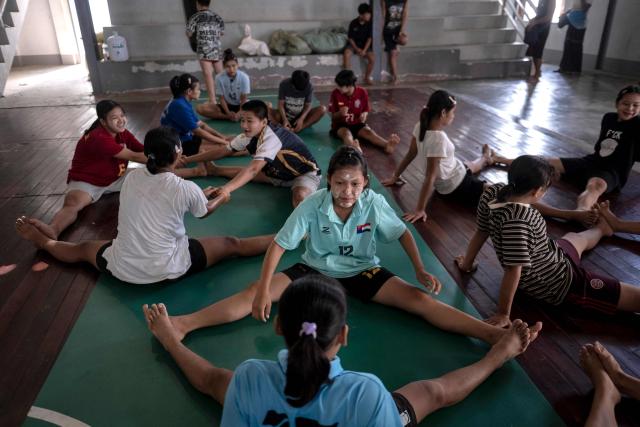 This photo taken on May 27, 2026 shows fighters stretching as they train in traditional Myanmar boxing known as Lethwei at a training camp in Hpa-an in Myanmar's Karen state. In a country consumed by conflict, a sport defined by brutality dominates: Myanmar's lethwei martial art, where headbutts are encouraged and knock-out blows are the aim of the game. (Photo by Sai Aung MAIN / AFP) / To go with AFP story Myanmar-conflict-lifestyle-box, FOCUS by Hla-Hla Htay and Joe Stenson