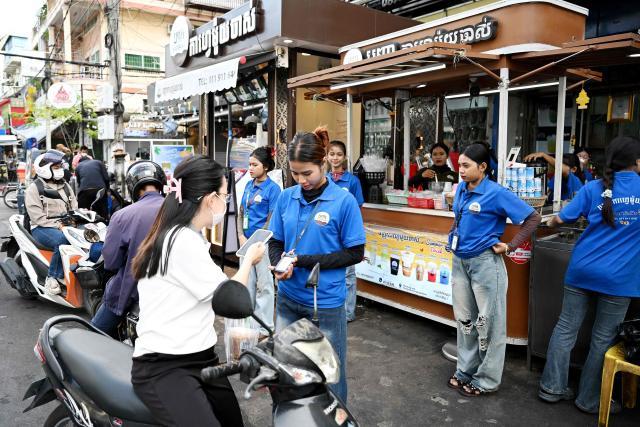 A woman scans a QR code of a bank as she buys coffee in plastic bag from a stall in Phnom Penh on September 4, 2026. (Photo by TANG CHHIN Sothy / AFP)