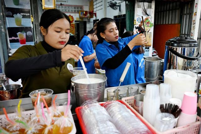 Workers make coffee for customers at a coffee stall in Phnom Penh on September 4, 2026. (Photo by TANG CHHIN Sothy / AFP)