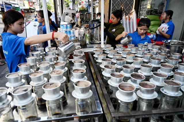 Workers pour hot water into coffee drip filters at a coffee stall in Phnom Penh on September 4, 2026. (Photo by TANG CHHIN Sothy / AFP)