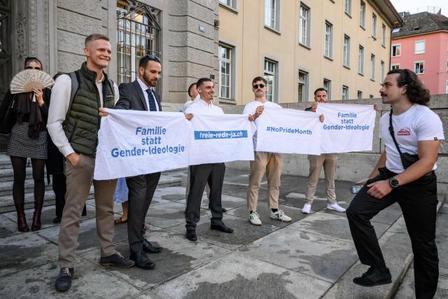 Tobias Lingg (L), a leading figure of the Swiss far-right group Junge Tat, poses next to a banner reading in German "Family instead of gender ideology" as he arrives at Zurich District Court for their trial, in Zurich, on September 4, 2026. Six people from the far-right group Junge Tat appeared before the Zurich District Court, accused of hatred-related offenses, coercion, rioting, property damage and trespassing. The group's two main leaders face up to six months in prison. (Photo by Fabrice COFFRINI / AFP)
