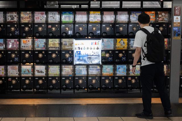 A man looks at Japanese capsule machines (Gashapon), with toys and trinkets, as he decides which one to pick in Tokyo on September 4, 2026. (Photo by Andrew CABALLERO-REYNOLDS / AFP)