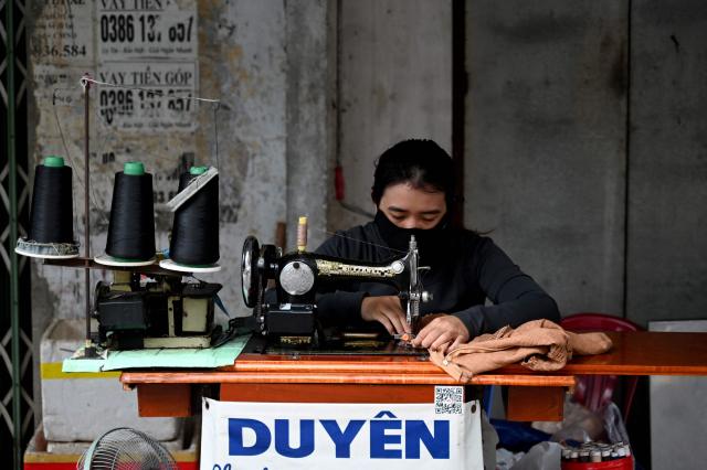 A woman sews on the sidewalk in Nha Trang, Vietnam's Khanh Hoa Province on September 4, 2026. (Photo by Nhac NGUYEN / AFP)