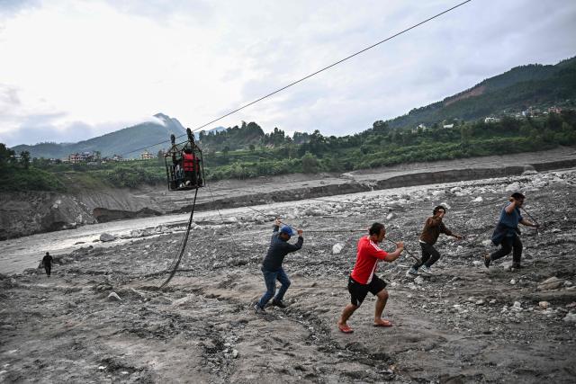 People pull a zip line to help others commute across the Trishuli River in the aftermath of flash floods at Trishuli Center in Nepal's Nuwakot district on September 4, 2026. Devastating floods on the China-Nepal border have killed at least 1,287 people in Nepal, the disaster authority said September 4, with the number of missing at 5,083. (Photo by Pedro Pardo / AFP)