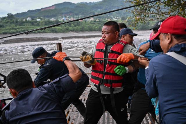 People pull a zip line to help others commute across the Trishuli River in the aftermath of flash floods at Trishuli Center in Nepal's Nuwakot district on September 4, 2026. Devastating floods on the China-Nepal border have killed at least 1,287 people in Nepal, the disaster authority said September 4, with the number of missing at 5,083. (Photo by Pedro Pardo / AFP)
