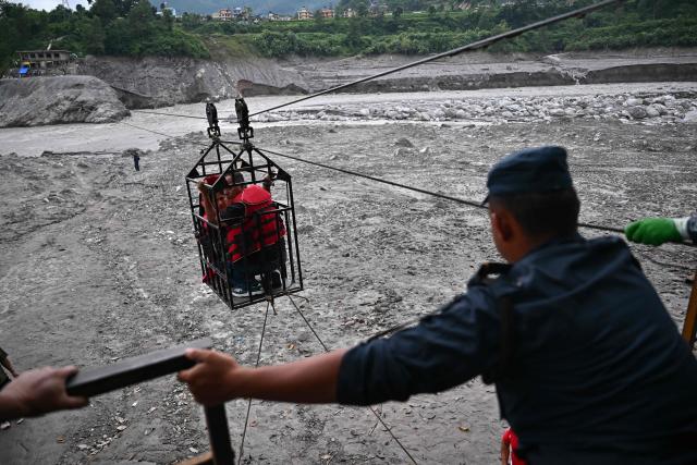 People commute across the Trishuli River via an installed zip line in the aftermath of flash floods at Trishuli Center in Nepal's Nuwakot district on September 4, 2026. Devastating floods on the China-Nepal border have killed at least 1,287 people in Nepal, the disaster authority said September 4, with the number of missing at 5,083. (Photo by Pedro Pardo / AFP)