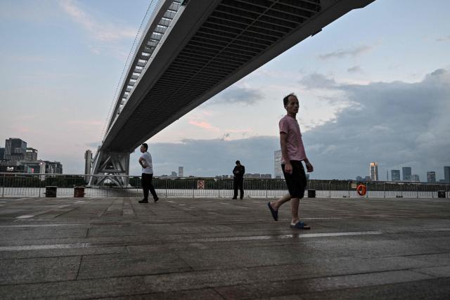 People walk next to the Huangpu river in Shanghai on September 4, 2026. (Photo by HECTOR RETAMAL / AFP)
