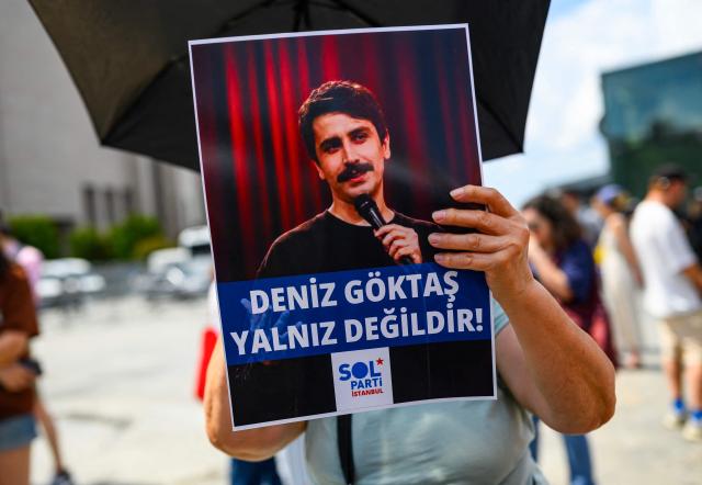 (FILES) A Turkish leftist chants slogans for Turkish comedian Deniz Goktas, who has been detained and brought before the court, holding a banner reading “Deniz Goktas  not alone”  in front of the Caglayan Courthouse on July 3, 2026. A Turkish court has indicted a comedian, notably on charges of insulting President Recep Tayyip Erdogan, following a satirical stand-up performance in June that could expose him to several years in prison, AFP learned on September 4. (Photo by Yasin AKGUL / AFP)