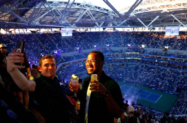 Spectators take a selfie while enjoying a Honey Deuce, the signature cocktail of the US Open, during the women's doubles first-round match between USA's Serena Williams and Venus Williams and Australia's Maya Joint and Taiwan's Chan Hao-ching on day six of the US Open tennis tournament at the USTA Billie Jean King National Tennis Center in New York City on September 4, 2026. (Photo by kena betancur / AFP)