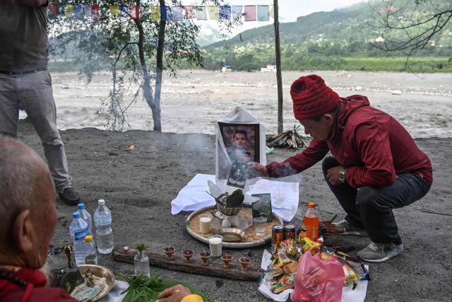 A man (L) sits by the river bank to pray for his son, a missing flash flood victim in Trishuli, in Nepal's Nuwakot district, on September 5, 2026. (Photo by Prakash MATHEMA / AFP)