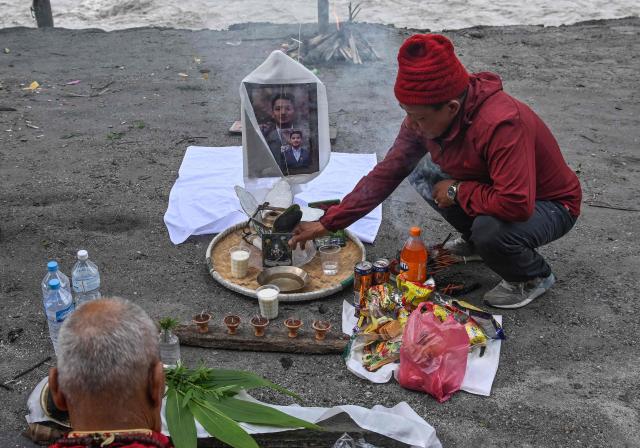 A man (L) sits by the river bank to pray for his son, a missing flash flood victim in Trishuli, in Nepal's Nuwakot district, on September 5, 2026. (Photo by Prakash MATHEMA / AFP)