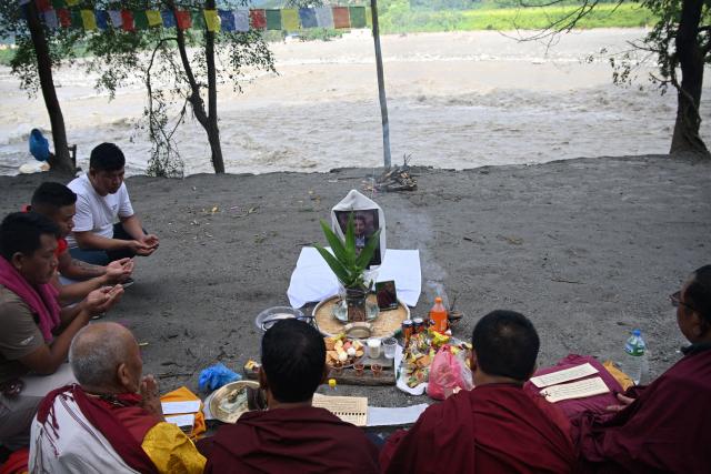 Lok Bahadur Sherpa (L), with monks performs the funeral rites of his son and flash flood victim Gymacho Sherpa along the Trishuli riverbank at Trishuli Bazar in Nepal's Nuwakot district on September 5, 2026. Devastating floods on the China-Nepal border have killed at least 1,287 people in Nepal, the disaster authority said September 4, with the number of missing at 5,083. (Photo by Prakash MATHEMA / AFP)