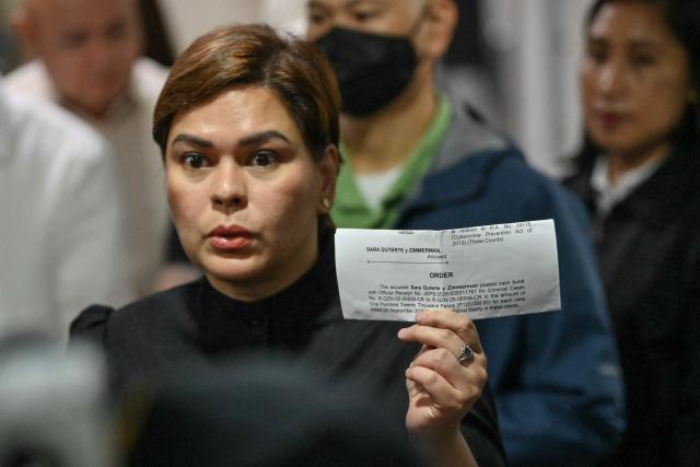 Philippine Vice President Sara Duterte shows a document after posting bail at a court building in Quezon City suburban Manila on September 5, 2026. A Philippine court on September 4 issued an arrest warrant for Vice President Sara Duterte over an alleged death threat against the country's president, with her defence team saying she would "exercise all her legal remedies". (Photo by Ted ALJIBE / AFP)