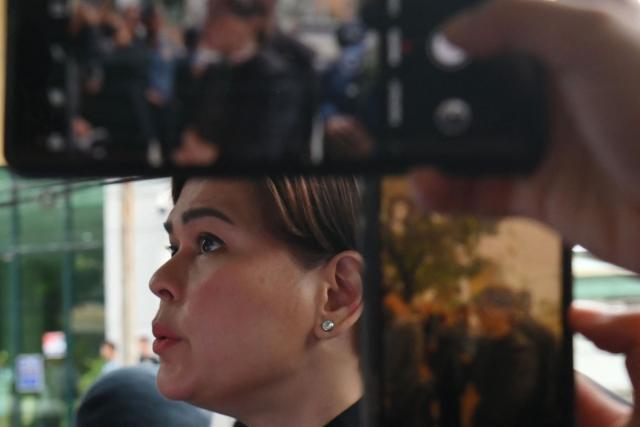 Philippine Vice President Sara Duterte is seen past mobile phones during her arrival at court to post bail in Quezon City, suburban Manila on September 5, 2026. Philippine Vice President Sara Duterte posted bail at a Manila courthouse on May 5, a day after an arrest warrant was issued over her alleged death threat against the country's president. (Photo by Ted ALJIBE / AFP)