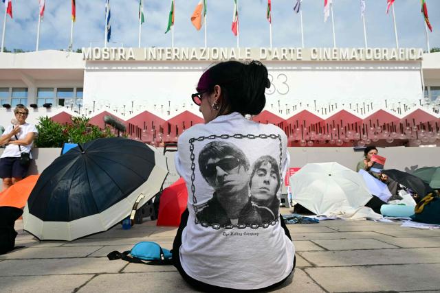 A person wearing a T-shirt of British rock band Oasis sits in front of the Palazzo del Cinema during the 83rd Venice Film Festival at Venice Lido on September 5, 2026. Noel Gallagher and his brother Liam Gallagher are expected in Venice today for the presentation of the movie "Oasis: Don’t Look Back in Anger" out of competition at the 83rd Venice Film Festival. (Photo by Stefano Rellandini / AFP)