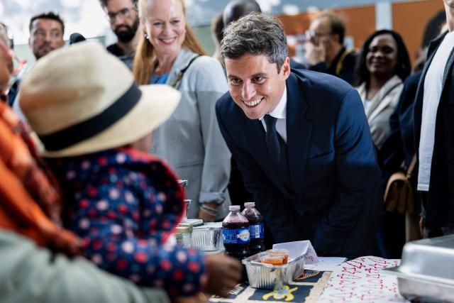 General Secretary of French centrist party Renaissance and 2027 presidential candidate Gabriel Attal (C) and Ensemble pour la Republique MP Violette Spillebout (C,L), a member of Attal's presidential campaign team, smiles to a child as he visits the Braderie de Lille flea market in Lille, northern France on September 5, 2026. (Photo by Sameer Al-DOUMY / AFP)