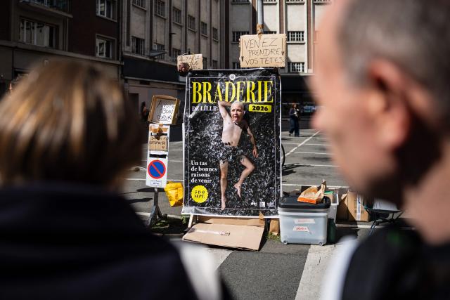 A woman poses for a picture through a poster of the Braderie de Lille flea market in Lille, northern France on September 5, 2025. (Photo by Sameer Al-DOUMY / AFP)