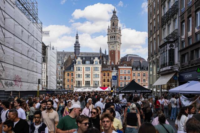 People walk past the Belfry of the Lille Chamber of Commerce during the Braderie de Lille flea market in Lille, northern France on September 5, 2025. (Photo by Sameer Al-DOUMY / AFP)