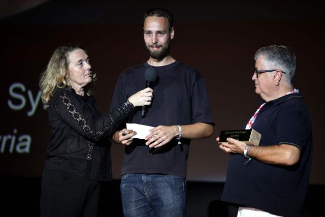 French photographer Philemon Barbier (C) stands by Delphine Lelu (L), co-founder of the Visa festival and André Bonet (R), Deputy Mayor of Perpignan in charge of culture, after receiving the Remi Ochlik prize awarded by the city of Perpignan during the 38th edition of the Visa pour l'image press photography festival in Perpignan, southern France, on September 5, 2026. (Photo by Valentine CHAPUIS / AFP)