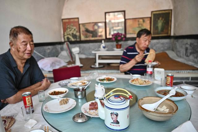 This picture taken on August 19, 2026 shows men eating at a restaurant in the Dazhai tourist area, in Jinzhong, in northern China's Shanxi province. In the ruling Communist Party's telling, Mao remains the revolutionary hero -- his face on banknotes, his portrait overlooking Tiananmen Square, and his body preserved in a mausoleum. (Photo by Pedro PARDO / AFP) / TO GO WITH: China-Mao-anniversary, by Sam DAVIES