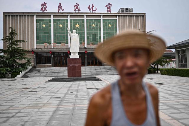 This picture taken on August 18, 2026 shows a man walking past in front of the late Communist leader Mao Zedong statue on the esplanade of the cultural center of Zhoujiazhuang Commune of Jinzhou, in China's northern Hebei province. (Photo by Pedro PARDO / AFP) / TO GO WITH: China-Mao-anniversary, by Sam DAVIES