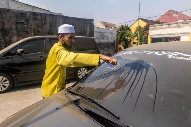A man clears volcanic ash from his car windscreen following the eruption of Mount Anak Krakatoa in Bogor, West Java on September 6, 2026. Mount Anak Krakatoa erupted on September 5, producing a fountain of lava and booming sounds that could be heard up to 700 kilometres (435 miles) away. (Photo by ADITYA Aji / AFP)