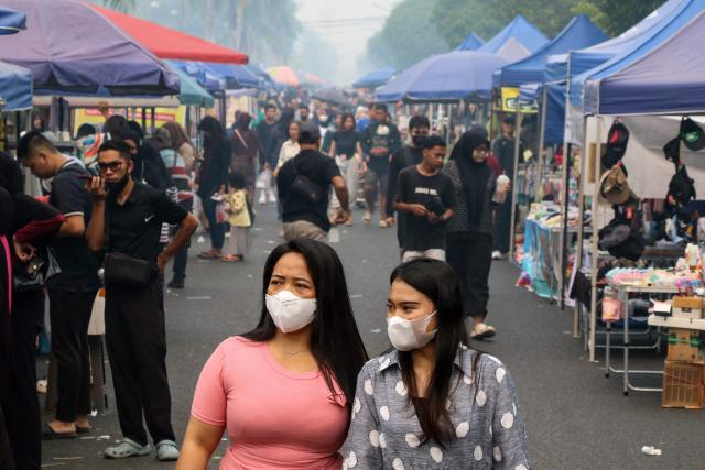 Women wearing face masks walk along a street market amid haze from forest and land fires shrouding the city of Palangka Raya in Central Kalimantan during Car-Free Day on September 6, 2026. (Photo by REINA / AFP)