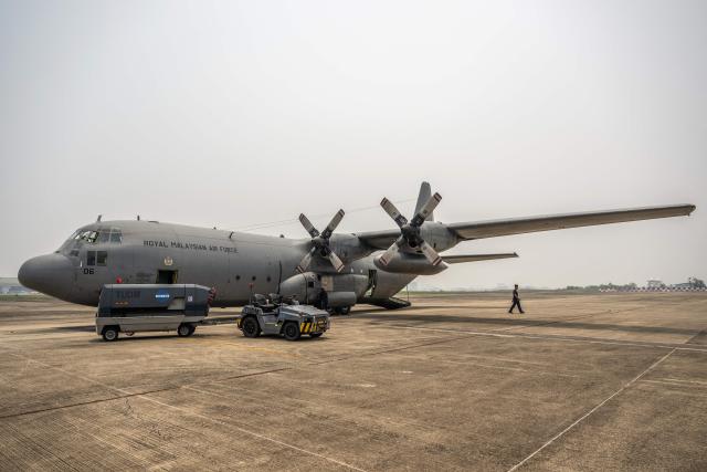 A member of the Royal Malaysian Air Force walks next to a C-130 aircraft preparing for a cloud-seeding operation at the air force base in Kuching, the capital of Sarawak state on the island of Borneo, on September 6, 2026. Malaysia launched a three-day cloud-seeding operation on September 3 in a bid to ease hazardous haze choking Sarawak state, as smoke from Indonesian forest fires pushed air quality to dangerous levels. (Photo by Mohd Rasfan / AFP)