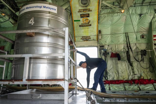A member of the Royal Malaysian Air Force inspects the hoses connected to cloud-seeding tanks aboard a C-130 aircraft at the air force base in Kuching, the capital of Sarawak state on the island of Borneo, on September 6, 2026. Malaysia launched a three-day cloud-seeding operation on September 3 in a bid to ease hazardous haze choking Sarawak state, as smoke from Indonesian forest fires pushed air quality to dangerous levels. (Photo by Mohd Rasfan / AFP)
