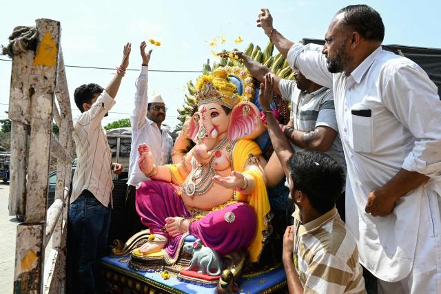Devotees shower flower petals over an idol of the elephant-headed Hindu deity Ganesha, after purchasing it from a workshop ahead of the Ganesh Chaturthi festival in Amritsar on September 6, 2026. (Photo by Narinder NANU / AFP)