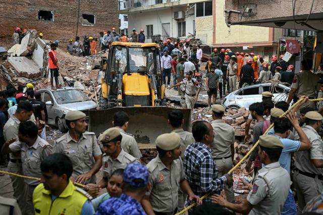 Security personnel cordon off the area as a bulldozer clears debris at the site following a building collapse in the Satya Niketan area in New Delhi on September 6, 2026. (Photo by Sajjad HUSSAIN / AFP)