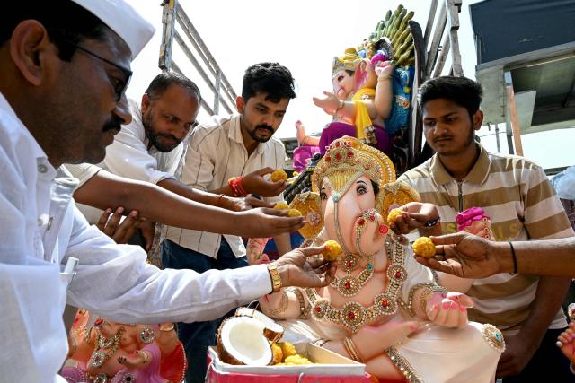 Devotees offer sweets to an idol of the elephant-headed Hindu deity Ganesha, after purchasing it from a workshop ahead of the Ganesh Chaturthi festival in Amritsar on September 6, 2026. (Photo by Narinder NANU / AFP)