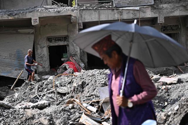 A man walks past damaged houses covered in sludge in the aftermath of flash floods in Trishuli, in Nepal's Nuwakot district on September 6, 2026. The glacial and mountain collapse on the China-Nepal border killed at least 1,384 people and left more than 5,500 missing across the two countries. (Photo by Pedro PARDO / AFP)