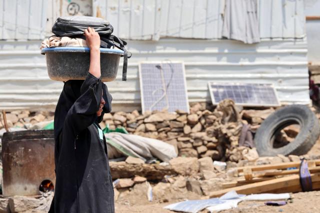 Carrying her belongings on her head, an internally displaced (IDP) Yemeni woman, one of many who fled their homes due to renewed clashes between Yemen's Saudi-backed government forces and the country's Houthi rebels, makes her way through a makeshift camp in the al-Kadah area of the Taiz Governorate, southwestern Yemen on September 6, 2026. Fighting between Yemeni government forces and Iran-backed Houthi rebels in southwest Yemen killed more than 140 combatants between midday September 5 and September 6, military sources said. Days-long clashes have erupted in Yemen over control of a gateway to the Red Sea in the deadliest fighting in the Arabian Peninsula country since a 2022 ceasefire between the two sides collapsed in July. (Photo by Ahmad AL-BASHA / AFP)