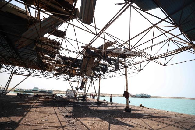 Men gather at the damaged port and storage and warehousing facilities following a US military strike earlier in the week on Kuhestak, Sirik County, in Iran's southern Hormozgan province on September 6, 2026. A deadly US strike hit a wedding celebration on the night of September 2, 2026, in the coastal town of Kuhestak along Strait of Hormuz in southern Iran, with the Iranian authorities  saying it killed at least four people, including a child, and wounded 68 others attending the wedding. The United States announced attacks against targets belonging to Iran's Revolutionary Guards. Iran has been at war since February 28, when the United States and Israel launched a surprise bombing campaign that killed its supreme leader. (Photo by ATTA KENARE / AFP) / 