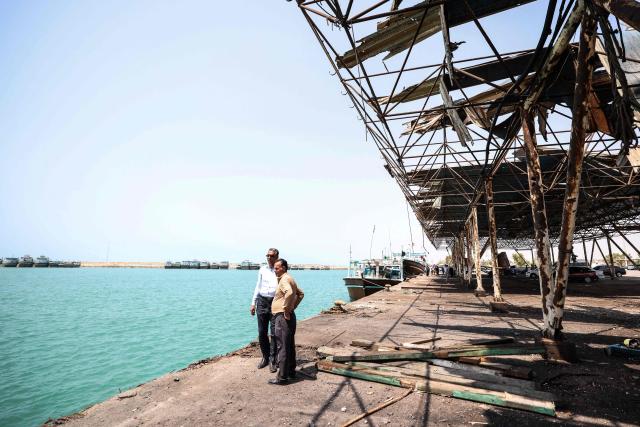 Men gather at the damaged port and storage and warehousing facilities following a US military strike earlier in the week on Kuhestak, Sirik County, in Iran's southern Hormozgan province on September 6, 2026. A deadly US strike hit a wedding celebration on the night of September 2, 2026, in the coastal town of Kuhestak along Strait of Hormuz in southern Iran, with the Iranian authorities  saying it killed at least four people, including a child, and wounded 68 others attending the wedding. The United States announced attacks against targets belonging to Iran's Revolutionary Guards. Iran has been at war since February 28, when the United States and Israel launched a surprise bombing campaign that killed its supreme leader. (Photo by ATTA KENARE / AFP) / 