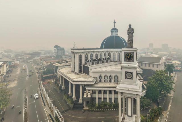 This aerial picture shows haze from land and forest fires blanketing the Cathedral Church in the city of Pontianak, West Kalimantan, on September 7, 2026. (Photo by BAY ISMOYO / AFP)