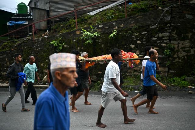Mourners carry the body of a flash flood victim during a funeral at Trishuli in Nepal's Nuwakot district on September 7, 2026. Nepali rescuers faced challenging conditions on September 6, as search operations after catastrophic floods entered a 12th day. The glacial and mountain collapse on the China-Nepal border killed at least 1,385 people and left more than 5,500 missing across the two countries. (Photo by Pedro PARDO / AFP)