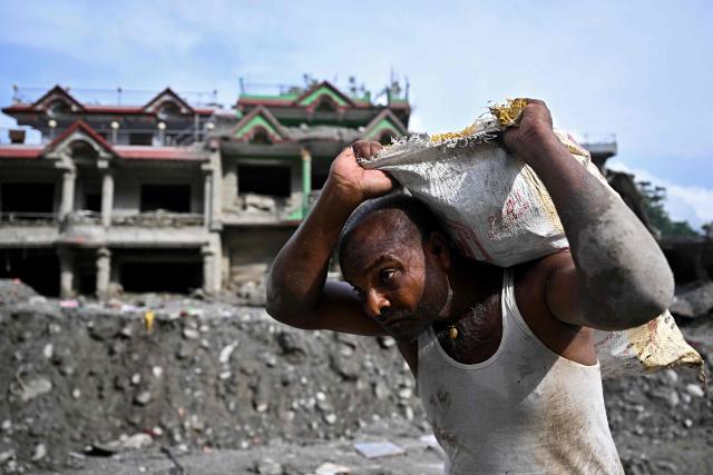 A man carries a sack in the aftermath of flash floods at Trishuli in Nepal's Nuwakot district on September 7, 2026. The August 26 glacial and mountain collapse on the China-Nepal border killed at least 1,385 people, with more than 5,500 missing across the two countries. (Photo by Pedro PARDO / AFP)