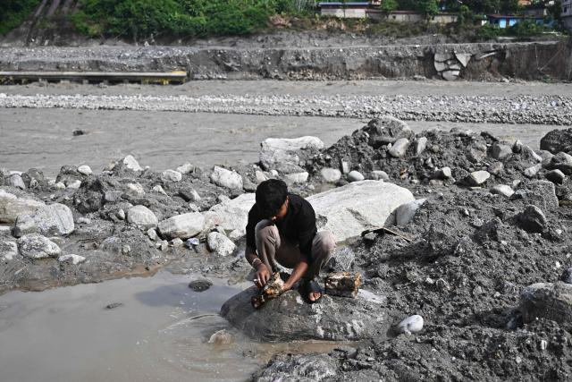 A man tries to recover his belongings in the aftermath of flash floods at Trishuli in Nepal's Nuwakot district on September 7, 2026. The August 26 glacial and mountain collapse on the China-Nepal border killed at least 1,385 people, with more than 5,500 missing across the two countries. (Photo by Pedro PARDO / AFP)