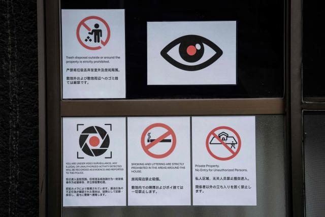 Notices warning against littering, smoking, and unauthorized entry ,written in multiple languages, are seen outside an apartment building near Shinjuku Station in Tokyo on September 7, 2026. Tokyo tourist hotspot Shinjuku will impose a ban on more than half of its holiday rentals including homes on Airbnb, an official said on September 7, after a surge in complaints about visitors. (Photo by Yuichi YAMAZAKI / AFP)