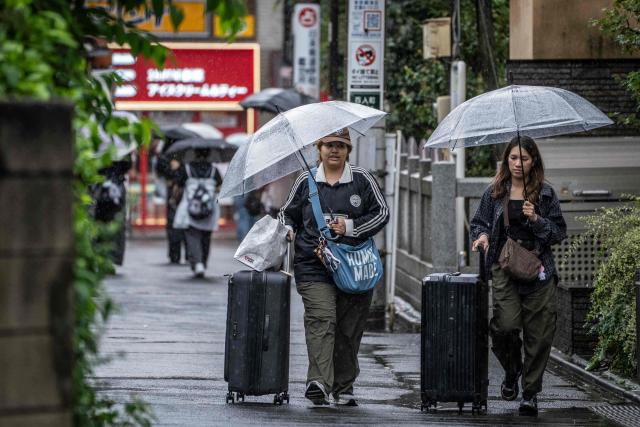 Foreign tourists pull their suitcases as they walk along a street near Shinjuku Station in Tokyo on September 7, 2026. Tokyo tourist hotspot Shinjuku will impose a ban on more than half of its holiday rentals including homes on Airbnb, an official said on September 7, after a surge in complaints about visitors. (Photo by Yuichi YAMAZAKI / AFP)