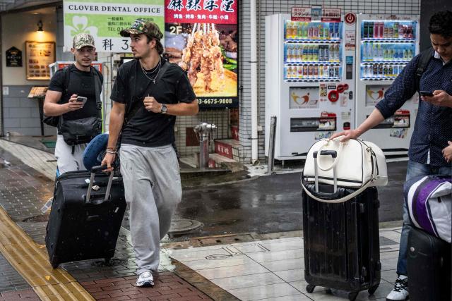 Foreign tourists pull their suitcases as they walk along a street near Shinjuku Station in Tokyo on September 7, 2026. Tokyo tourist hotspot Shinjuku will impose a ban on more than half of its holiday rentals including homes on Airbnb, an official said on September 7, after a surge in complaints about visitors. (Photo by Yuichi YAMAZAKI / AFP)