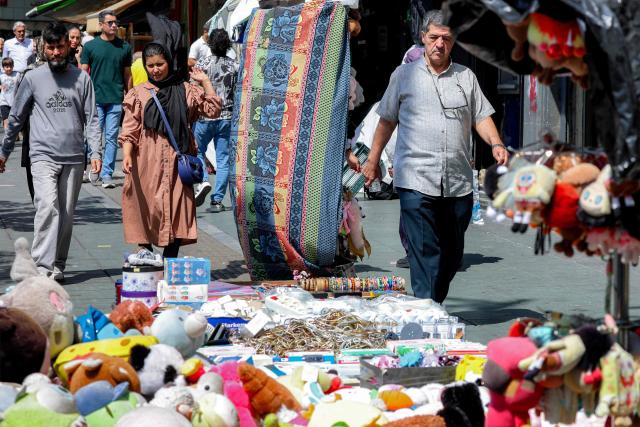 People walk past vendors' merchandise along a market street in Tehran on September 7, 2026. Iran's top negotiator threatened on September 6 of a more forceful response to any further US attacks after Tehran targeted American warships in their latest round of clashes. The exchanges of fire, which began with US raids last week, come amid a deadlock in the six-month war between the two foes. (Photo by AFP) / 