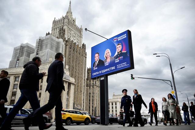 Pedestrians walk past the Russian Foreign Ministry building and a campaign poster for the election to the Russian State Duma (lower house of Russia's Parliament) in Moscow on September 7, 2026. Russia will vote for the Duma's election on September 18-20, 2026. (Photo by Alexander NEMENOV / AFP)