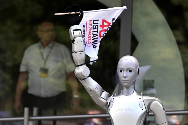 A humanoid robot waves a flag during a demonstration calling for the regulation of artificial intelligence development in Warsaw on September 7, 2026. Waving flags, "chanting" slogans, and marching in circles -- around thirty robots took to the streets to raise awareness for AI regulation in front of the digital affairs ministry on September 7, 2026. (Photo by Sergei GAPON / AFP)